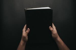Hands holding up book with black cover