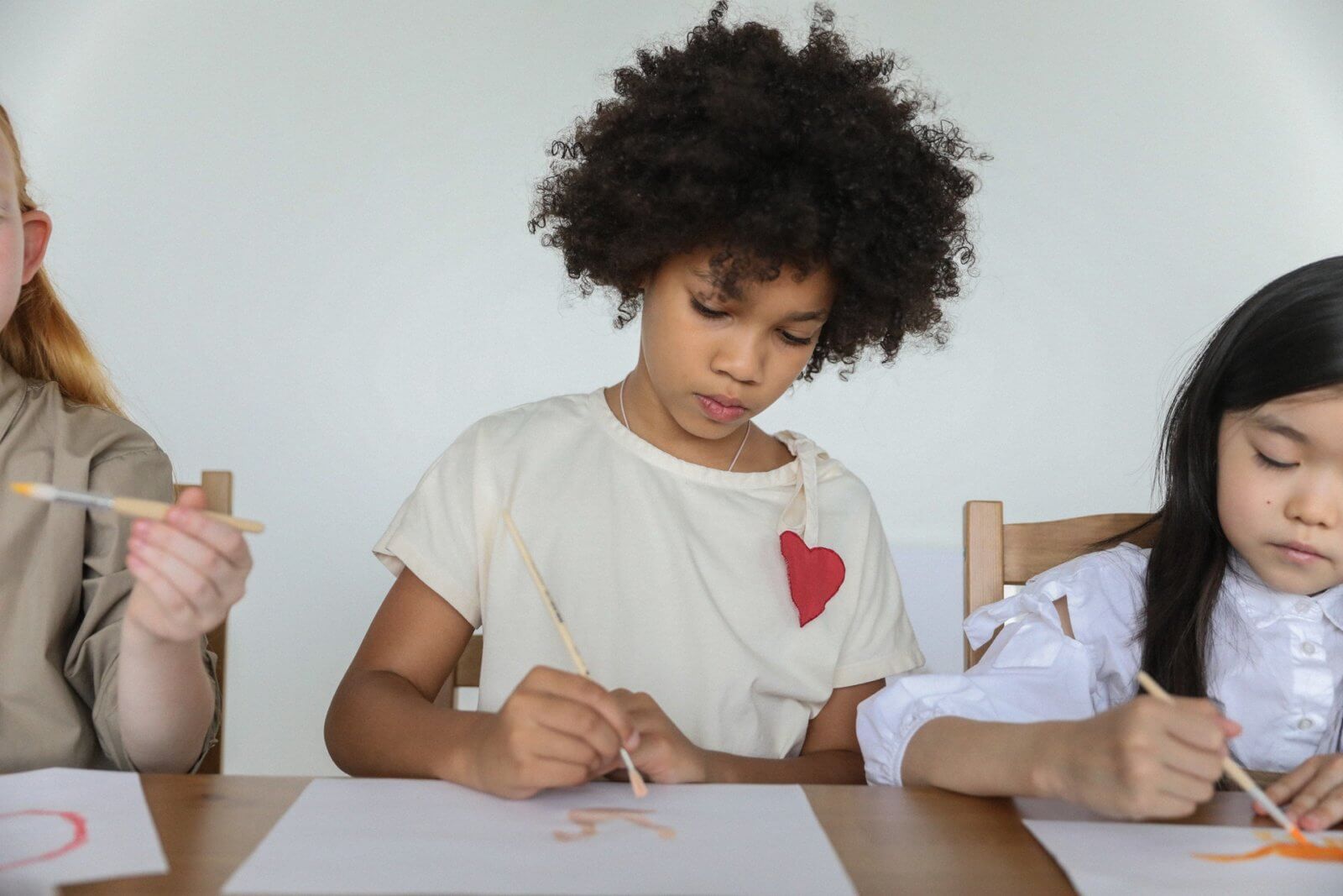 Three children painting at a table together