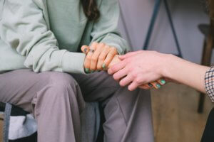 Two people sitting and holding hands