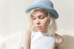 Blonde girl with light blue hat looking down