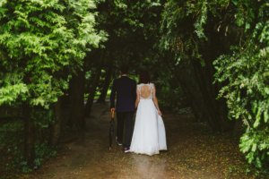 Bride and groom walking under canopy of trees